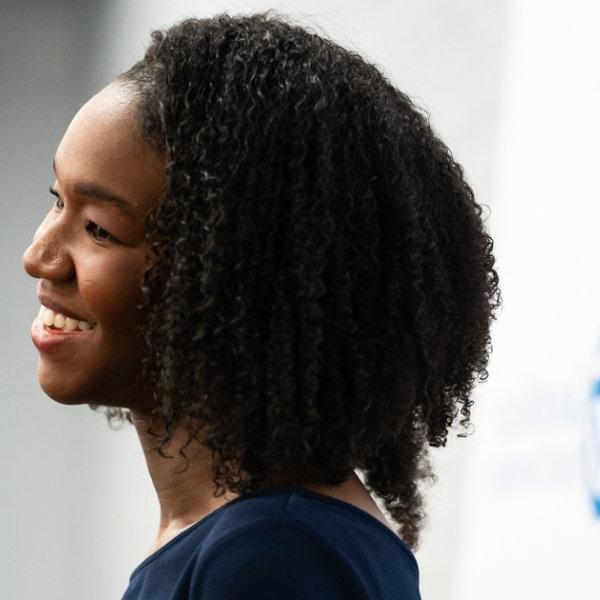 Krya Harris Bolden smiles against a photo backdrop with the GVSU word mark printed on it