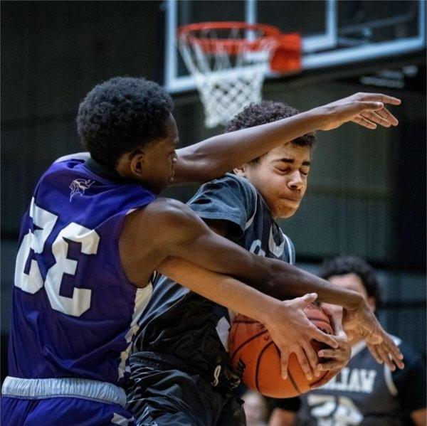 Two youth basketball players clash for a rebound during a game.