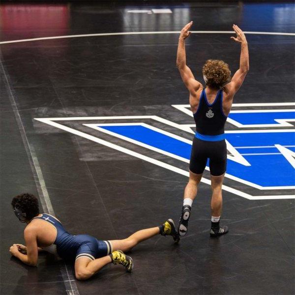 wrestler holds both arms up in victory near the GV on a wrestling match